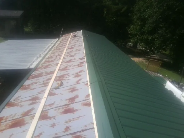 Old rusted panels beside newly installed green metal roofing — Wind Damage Roof Repair by Roofing Brothers in Templeton