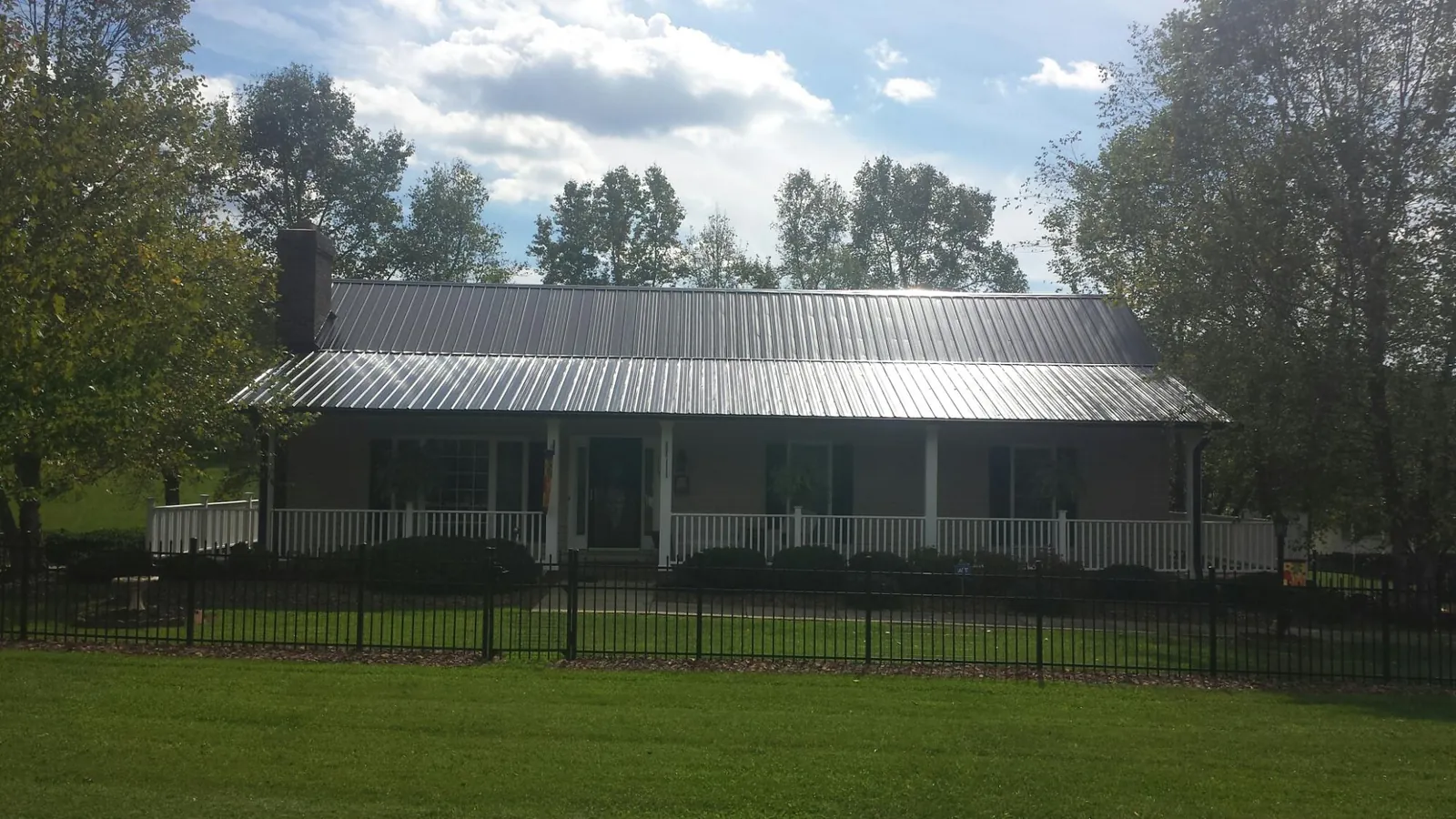 Gray metal roof on a brick ranch with a full width front porch — Gutter Guard Installation work by our crew in Templeton